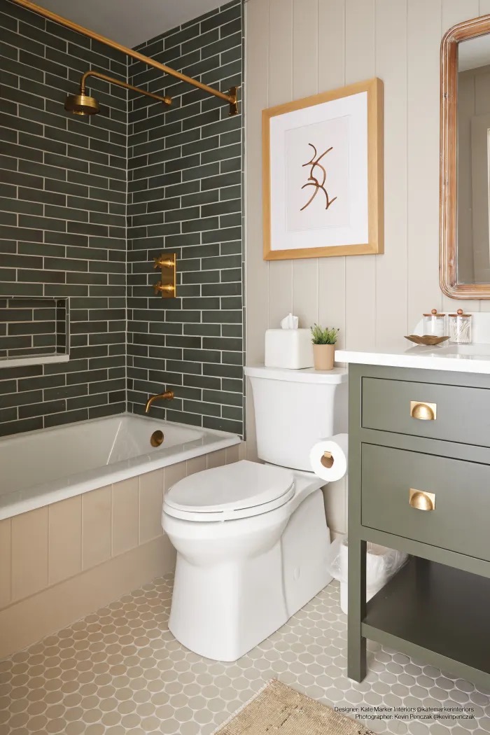 Deep green subway tile tub surround with brass fixtures and penny-round floor